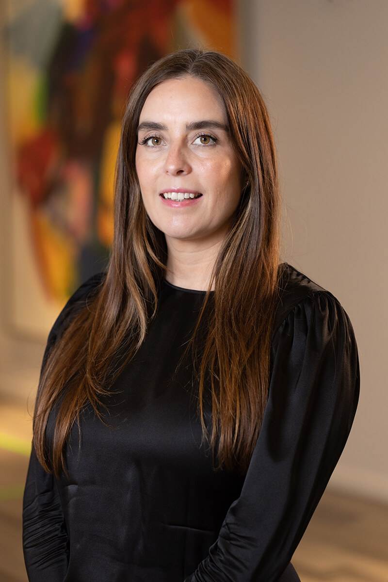 Professional portrait of MariCarmen Ramos from Triple A Restaurant Group, wearing a black blouse and smiling in a modern office setting — representing leadership, confidence, and excellence in hospitality operations.