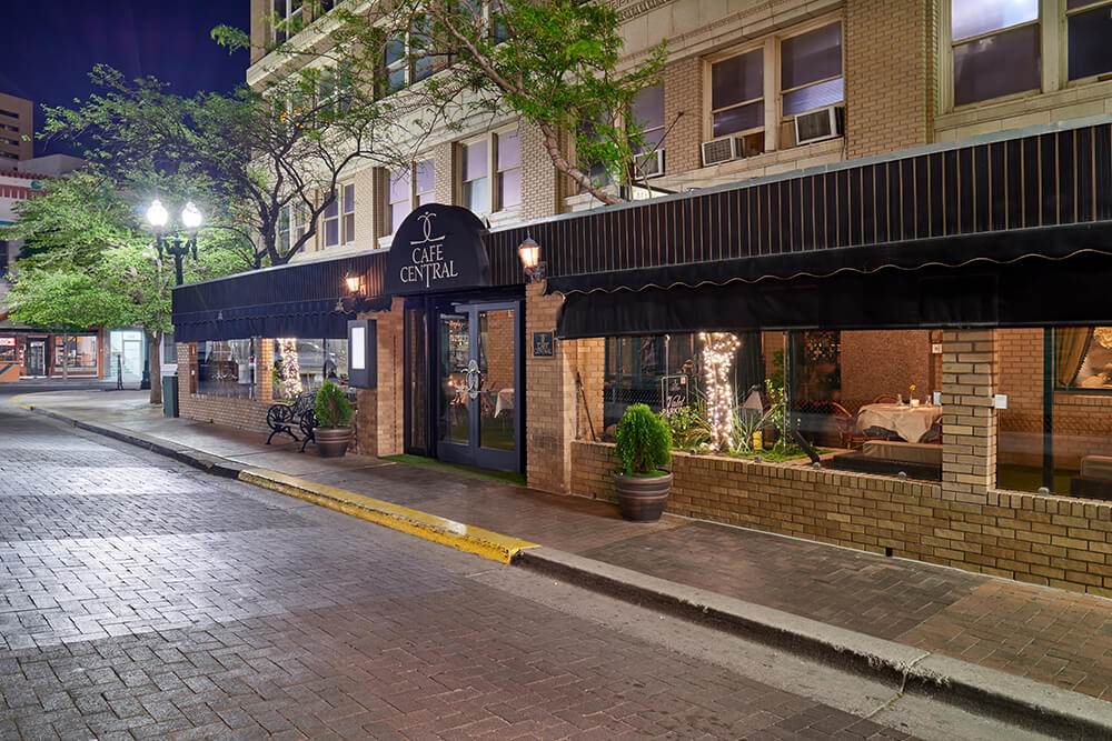 Exterior of Café Central in downtown El Paso, featuring elegant black awnings, soft evening lighting, and a charming entrance—welcoming guests to a fine dining experience in a historic, upscale setting.