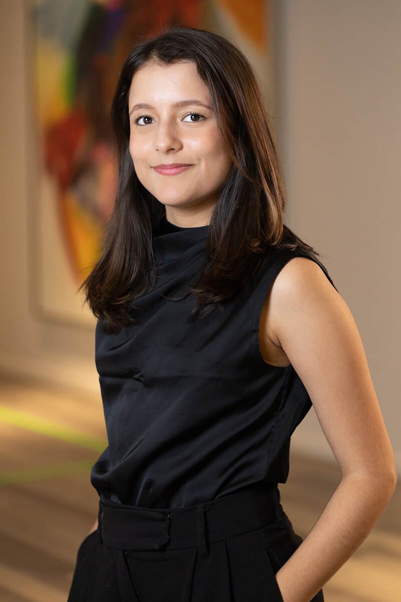 Ariana Martinez of Triple A Restaurant Group, confidently posing in a professional setting with modern art in the background — representing leadership, creativity, and excellence in the hospitality industry.